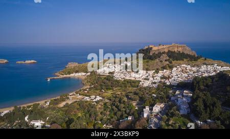 Drohnenaufnahme, Lindos, Akropolis von Lindos, Licht am späten Nachmittag, Blick auf ein Dorf mit einer Festung auf einem Hügel neben einer Strandbucht, archäologische Stätte Stockfoto