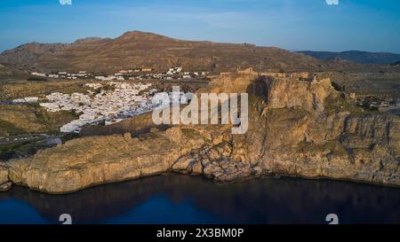 Drohnenaufnahme, erstes Morgenlicht, Lindos, Akropolis von Lindos, Ruinen einer alten Festung über einem Dorf an der Küste in der Abenddämmerung, archäologische Stätte Stockfoto