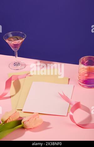 Ein Stapel weißer und gelber Papiere, angeordnet mit rosa Bändern und Tulpenblüten. Es gibt zwei verschiedene Arten von Weingläsern. Leerzeichen kopieren ein Stockfoto
