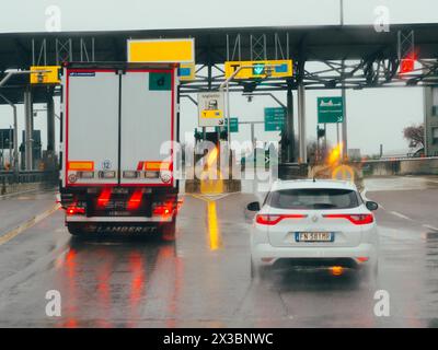 Auto wartet an einer Mautstelle mit Ampeln und Zahlspuren an einem regnerischen Tag, Autobahn A1 A8 in der Nähe von Mailand, Italien Stockfoto