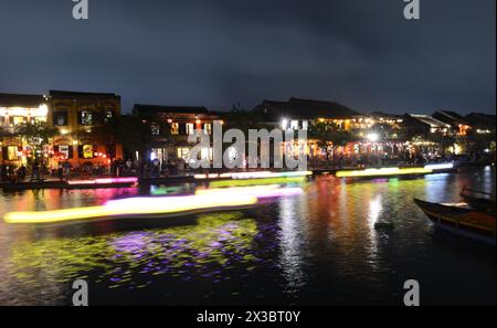 Mit Laternen beleuchtete Holzboote nehmen Einheimische und Touristen mit auf einen Ausflug auf dem Fluss Thu Bon in der Altstadt von Hoi an, Vietnam. Stockfoto