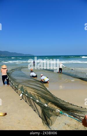 Vietnamesische Fischer ziehen ein großes Fischernetz vom Strand in da Nang, Vietnam. Stockfoto