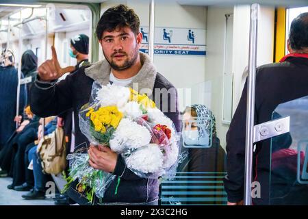 Teheran, Iran, 22. Dezember 2022: Porträt eines jungen iranischen Mannes mit einem Blumenstrauß in der U-Bahn. Blumenhändler Stockfoto