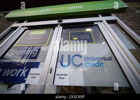 Aktenfoto vom 10/21 mit einem Universal Credit-Zeichen an der Tür eines Jobcenters plus im Osten Londons. Jedes Scheitern bei der Umstellung von Menschen auf Universal Credit aus älteren, so genannten Legacy-Vorteilen könnte zu "wirklichem Elend für Tausende" führen, warnten die Abgeordneten. Das Ministerium für Arbeit und Pensionen (DWP) muss sicherstellen, dass es den Antragstellern, von denen einige „schutzbedürftig“ sind, hilft, zu wechseln und ihre Leistungen nicht zu verlieren, heißt es in ihrem Bericht. Ausgabedatum: Freitag, 26. April 2024. Stockfoto