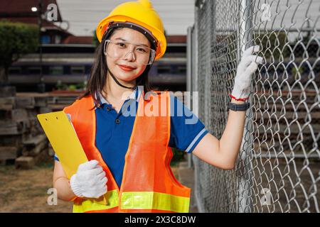 Portrait junger Frauen, die mit einem glücklichen Lächeln stehen, mit einem Schutzhelm. Kluge Mitarbeiterin, die in der Industrie arbeitet. Stockfoto