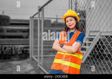 Portrait junger Frauen, die mit einem glücklichen Lächeln stehen, mit einem Schutzhelm. Kluge Mitarbeiterin, die in der Industrie arbeitet. Stockfoto