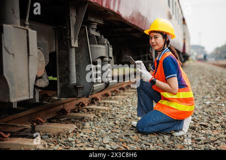 Lokomotivingenieur weibliche Arbeiter. Junge Teenager Asiatische Arbeitsüberprüfung Service Wartung Zug mit Tablet Computer Software. Stockfoto