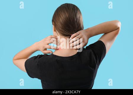 Junge Frau mit Mückenspray auf blauem Hintergrund, Rückansicht Stockfoto