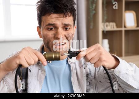 Ein Mann mit einem Stromschlag, verbranntem Gesicht und Stecker zu Hause, Nahaufnahme Stockfoto