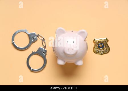 Schweinebank mit Handschellen und Polizeiabzeichen auf orangem Hintergrund Stockfoto