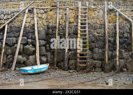 Kleines Ruderboot, das bei Ebbe am Ufer des Clovelly Harbour in Devon vor Anker liegt. Stockfoto