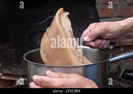 Der Koch nimmt ein Stück langsam gekochtes Rindenfleisch aus dem Topf, um eine Brühe in einer rustikalen Küche zu machen, Kopierraum, ausgewählter Fokus, enge Tiefe der fette Stockfoto