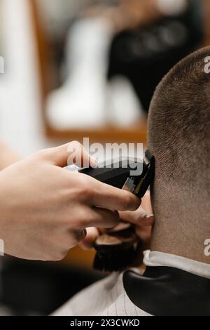 Der Friseur verwendet Haarschneider an der Stirn, am Ohr, am Kinn, am Tempel Stockfoto