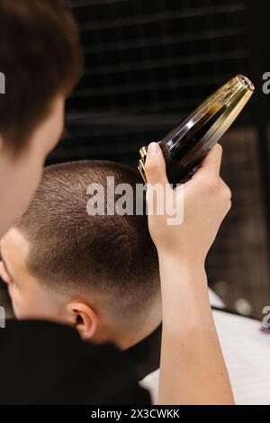 Der Friseur verwendet Haarschneider an der Stirn, am Ohr, am Kinn, am Tempel Stockfoto