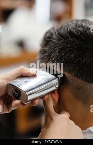 Der Friseur verwendet Haarschneider an der Stirn, am Ohr, am Kinn, am Tempel Stockfoto