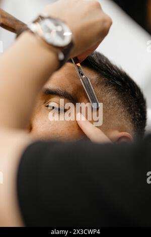 Ein Mann, der in einem Friseurladen sitzt und seinen Bart vom Friseur rasiert Stockfoto