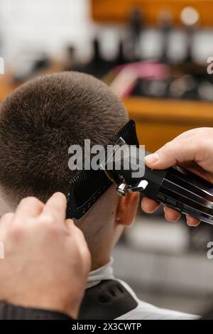 Der Friseur verwendet Haarschneider an der Stirn, am Ohr, am Kinn, am Tempel Stockfoto