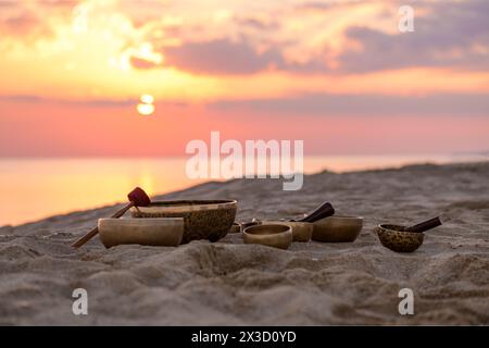 Tibetische Klangschalen mit Stöcken am Meer bei schönem Sonnenuntergang Stockfoto