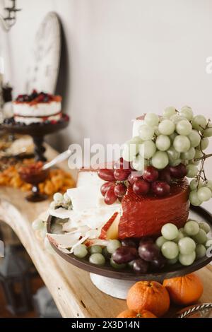Handwerklich hergestellte Käseplatte mit lebendigen Trauben und Orangen. Stockfoto