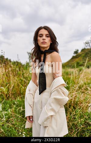 Eine schöne junge Frau steht in weiß gekleidet auf einem Feld und genießt die sanfte Sommerbrise. Stockfoto