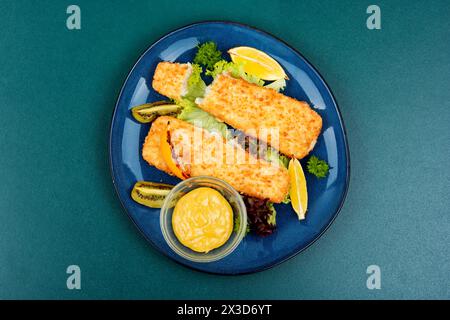 In Semmelbröseln gebratenes Pollock-Filet mit Soße und Kiwi. Fisch in Chips. Stockfoto