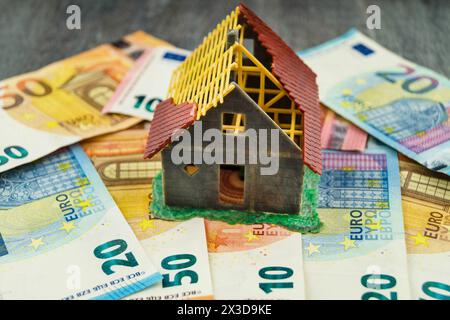 Unvollendetes Modellhaus auf Euro-Münzen als Symbol für den Anstieg der Immobilienpreise Stockfoto