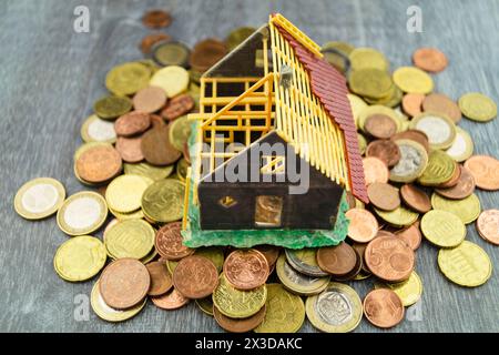Unvollendetes Modellhaus auf Euro-Münzen als Symbol für den Anstieg der Immobilienpreise Stockfoto