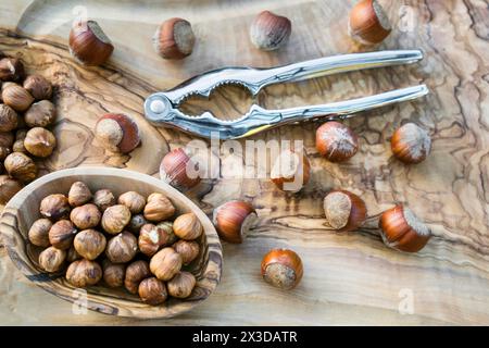 Haselnuss (Corylus avellana), Haselnüsse, ganz und zerrissen, in einer Schüssel, mit Nussknacker Stockfoto