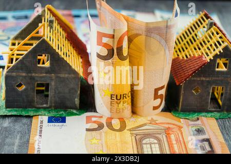 Unvollendete Modellhäuser auf Euro-Münzen, die den Anstieg der Immobilienpreise symbolisieren Stockfoto