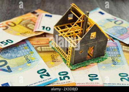 Unvollendetes Modellhaus auf Euro-Münzen als Symbol für den Anstieg der Immobilienpreise Stockfoto