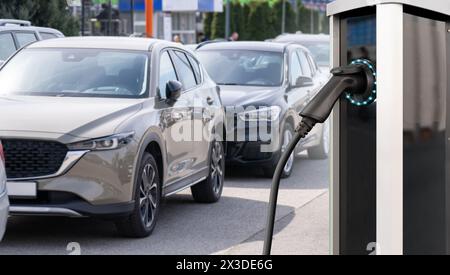 Ladestation für Elektrofahrzeuge auf dem Hintergrund einer Reihe von Autos. Konzept. Stockfoto