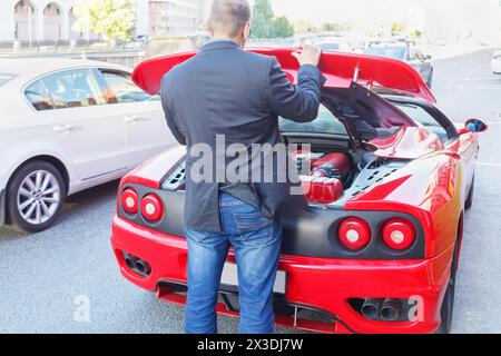 MOSKAU, RUSSLAND - 22. Juni 2016: Erfolgreicher Geschäftsmann (mit Modellveröffentlichungen) hebt den Stoßfänger des Luxus-Roadsters Ferrari von hinten an Stockfoto