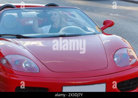 MOSKAU, RUSSLAND - 22. Juni 2016: Junge Frau (mit Modellveröffentlichungen), die hinter dem Rad sitzt und einen roten Luxus-Roadster Ferrari fährt Stockfoto