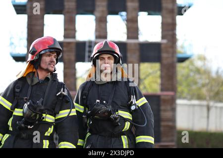 Zwei Feuerwehrleute in Ausrüstung und rote Helme auf dem Testgelände Stockfoto