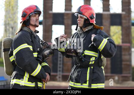 Zwei Feuerwehrleute in Ausrüstung und rote Helme auf dem Testgelände, führen die Diskussion Stockfoto