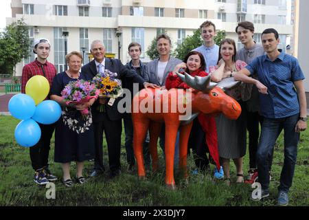 Familienfoto mehrerer Generationen (Enkel, Kinder, Eltern mit Modellveröffentlichungen) mit Holzskulptur von Elchen im Innenhof des mehrstöckigen B Stockfoto