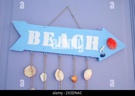 Die Inschrift Strand auf dem hölzernen Schild in Form von Pfeilen an der lila Tür Stockfoto