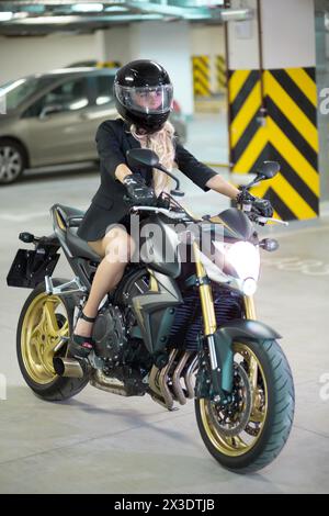 Ein Mädchen mit langen Haaren und Helm sitzt auf dem Fahrrad. Stockfoto