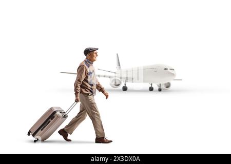Profilaufnahme eines älteren Mannes, der einen Koffer zieht und auf ein Flugzeug zugeht, das auf weißem Hintergrund isoliert ist Stockfoto