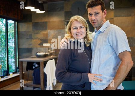 Ein lächelnder junger Mann und eine junge Frau stehen umarmt in der Garderobe im Badehaus. Stockfoto