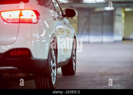 Rechte Seite des weißen Fahrzeugs mit eingeschalteter Schlussleuchte und Bremsleuchte, Rückansicht. Stockfoto