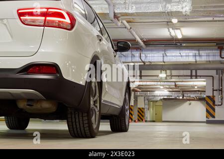 Rechte Seite des weißen Autos in der Tiefgarage, geringer Winkel von hinten. Stockfoto