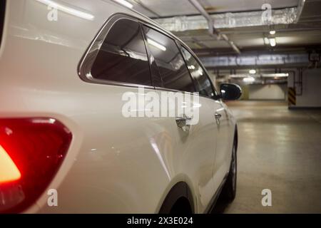 Rechte Seite des weißen modernen Autos an der Tiefgarage, seitliche Rückansicht. Stockfoto