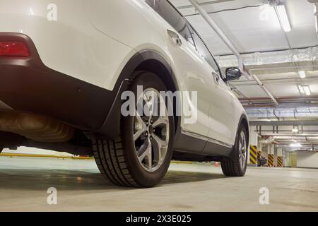 Weißer Sportwagen in der Tiefgarage, flacher Winkel, seitliche Rückansicht. Stockfoto