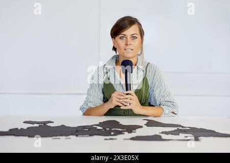 Die junge Frau sitzt am Schreibtisch mit der Karte der Puzzle-Welt. Stockfoto