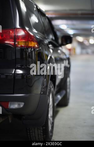 Rechte Seite des schwarzen Autos an der Tiefgarage, Rückansicht. Stockfoto