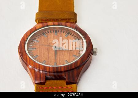 Hölzerne Armbanduhr mit Lederarmband auf weißem Hintergrund. Stockfoto