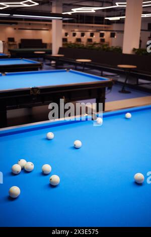 Ungeordnete weiße Kugeln auf blauem Billardtisch im Club. Stockfoto