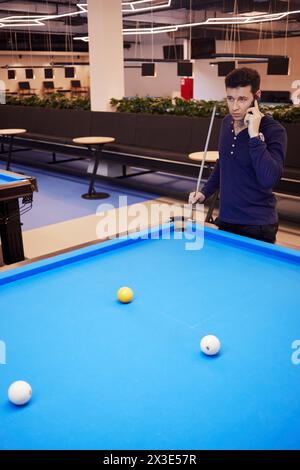 Der Mann redet mit dem Handy in der Nähe des Billardtisches im Billardclub. Stockfoto