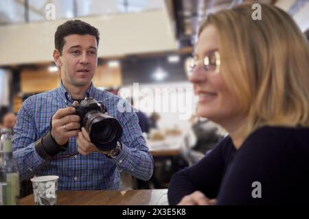 Ein Mann mit Kamera macht Fotos von einer Frau im Café. Stockfoto